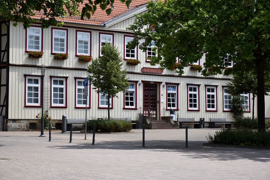 Exteriör av ett rathaus med vita väggar, röda fönsterramar och blomlådor.
