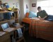 Young man reading on bed in dorm room, smiling, side view